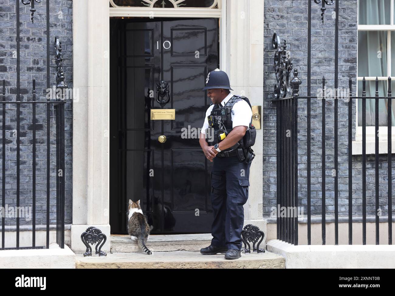 Larry the resident No.10 mouse catcher waiting to be let in by British bobby on Downing Street, Westminster, London, UK [SPE2XNNT0B]