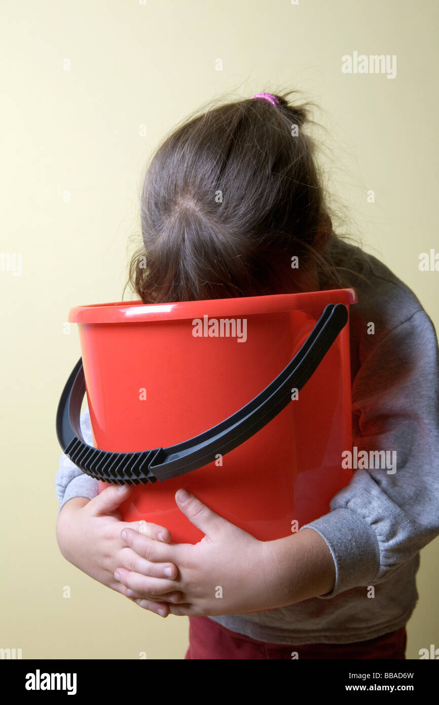 A young girl being sick in a bucket Stock Photo